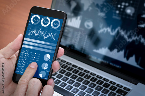 Investor analyzing stock market report and financial dashboard with business intelligence (BI), with key performance indicators (KPI).Businessman using smart phone with laptop computer. photo