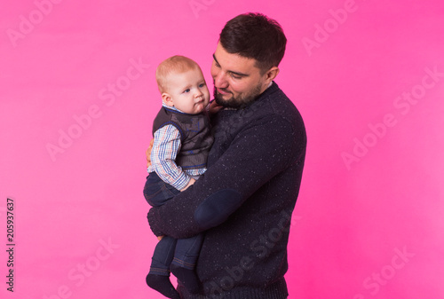 happy father with a baby son isolated on a pink background