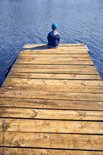 Dreamer, silhouette of boy sits on the lake wooden pier , psychology concept
