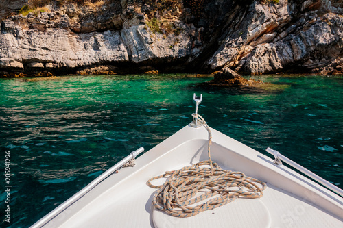 Summer time view from yacht gangway on the rocky cliff, Azure clear waterr near cliff. Boat trip.island Greece.the stern of the yacht with a rope and anchor photo