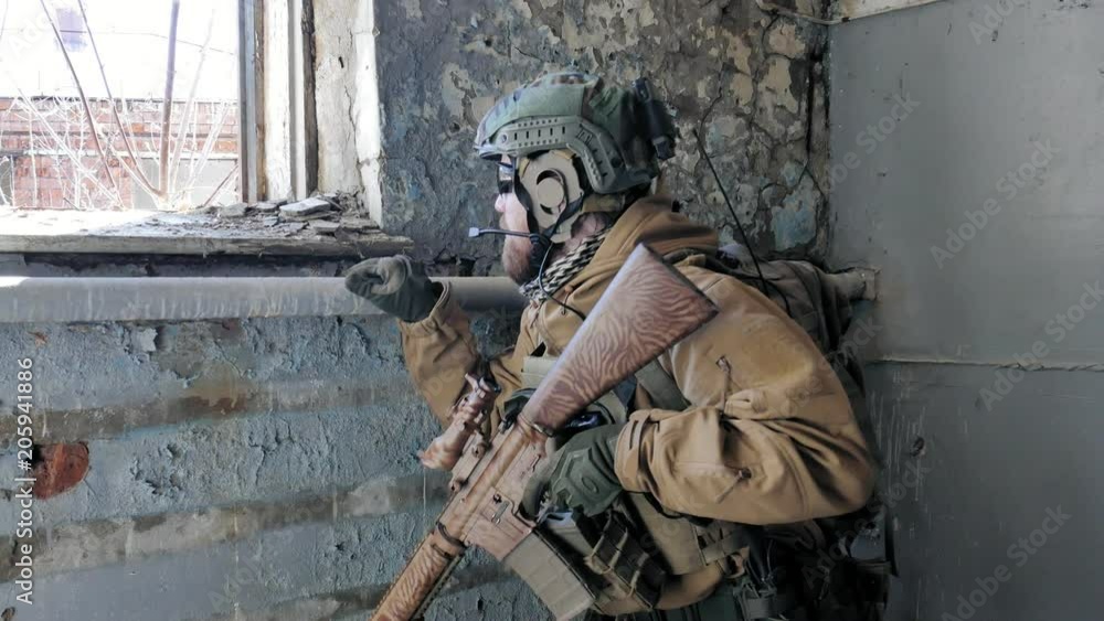 Soldiers in camouflage with a military weapon aiming through the rifle sight through the window of an old building, the military concept Soldiers in camouflage with a military weapon aiming through the rifle sight through the window of an old building, the military concept