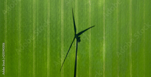 Drone view of an agricultural land with the silhouette of a wind turbine