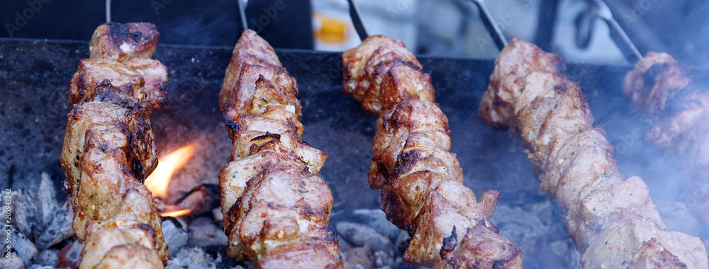 Marinated barbecue meat on skewer. Shish kebab or Shashlyk meaning skewered  meat. Beef or pork on grill on an open fire with smoke. Street food, picnic  concept Stock Photo