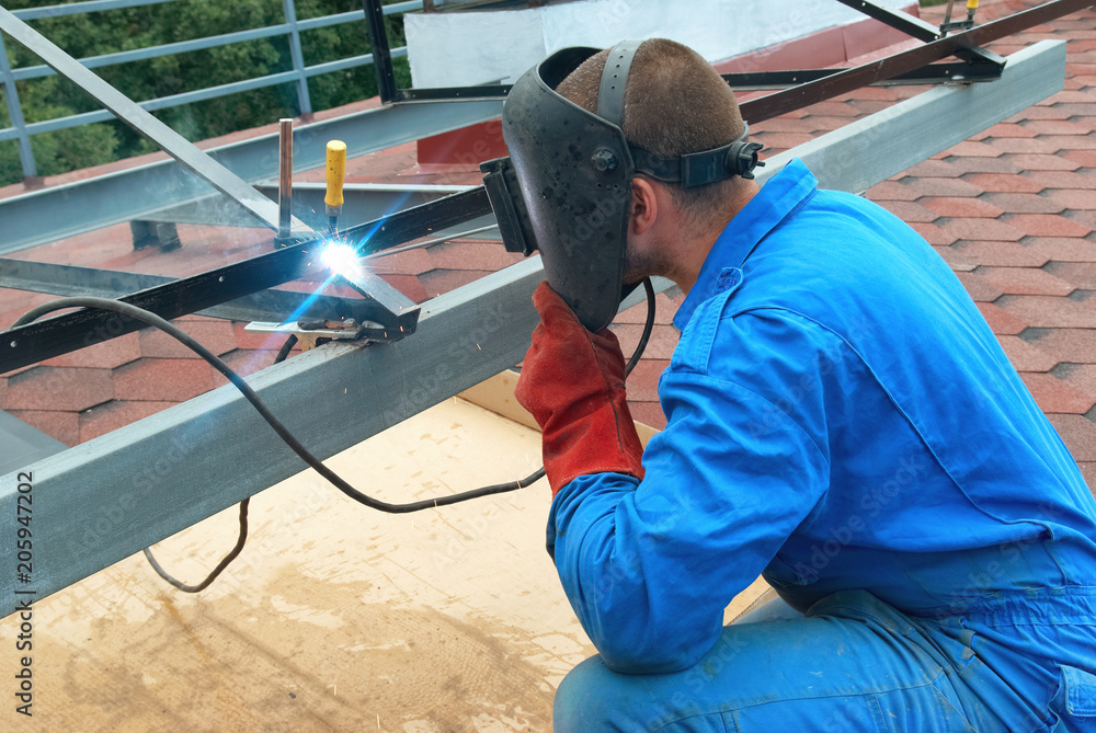 Man at work: welder worker on constructiion site working with metal construction Man at work: welder worker on constructiion site working with metal construction
