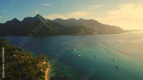 Aerial view of tropical paradise shore of Moorea island, lush jungle, scenic hills and mountains around Opunohu Bay at sunset - South Pacific Ocean, French Polynesia landscape from above, 4k photo