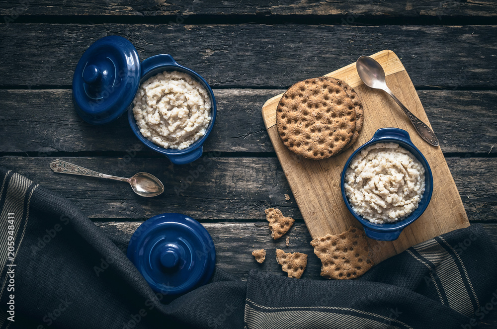 Barley porridge in the blue ceramic pot and bread on dark aged wooden background. Healthy breakfast. Barley porridge in the blue ceramic pot and bread on dark aged wooden background. Healthy breakfast.