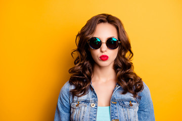 Portrait of trendy cool girl in summer glasses sending kiss with pout lips having fashionable look modern hairdo isolated on yellow background. Rest relax leisure fun concept