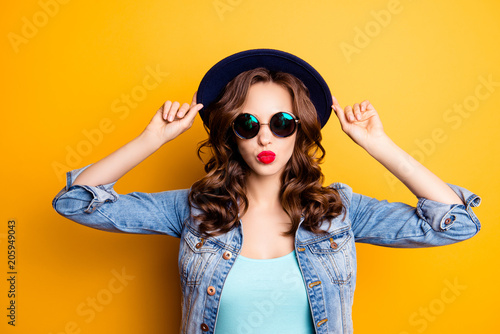 Vászonkép Portrait of cool charming girl holding hat on her head sending kiss with pout li