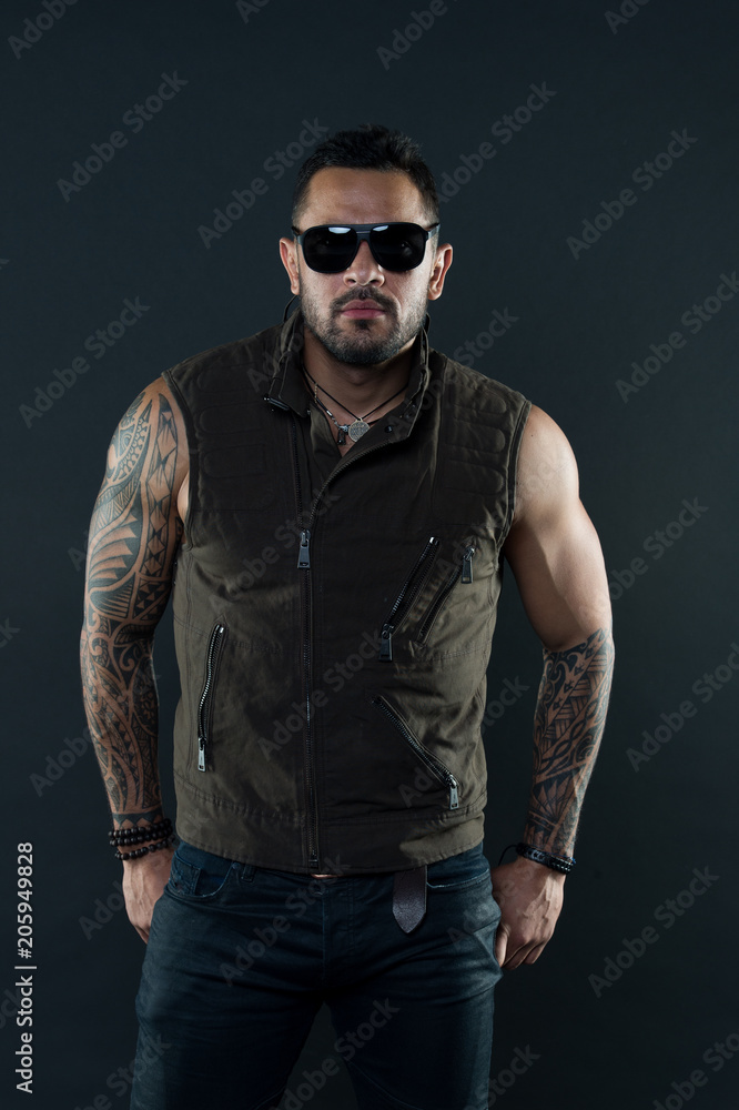 Fashion style and trend. Tattoo model with beard on unshaven face. Bearded man with tattoo on strong arms. Tattooed man with biceps and triceps. Fashion macho in trendy sunglasses Fashion style and trend. Tattoo model with beard on unshaven face. Bearded man with tattoo on strong arms. Tattooed man with biceps and triceps. Fashion macho in trendy sunglasses