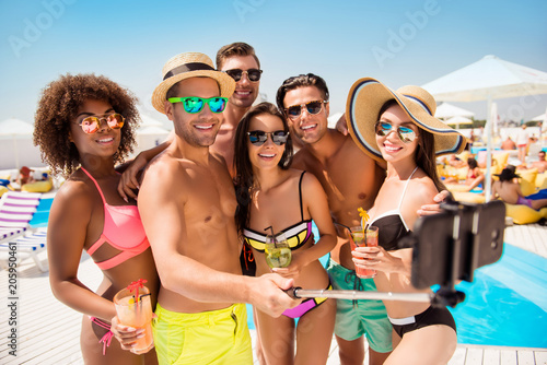 Diversity sunbathing sunshine tanned happiness eyewear spectacles cell cellphone modern technology video call concept. Group of excited funky fashionable amusing joyful teens taking selfie