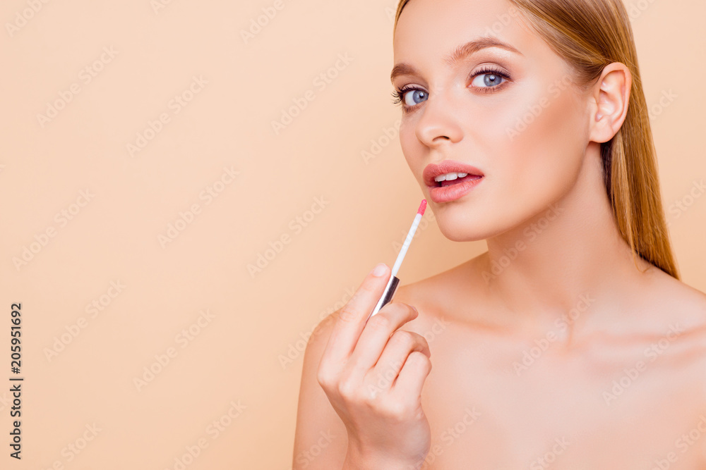 Portrait with copy space empty place for product of pretty trendy stylish girl testing new lip gloss isolated on beige background, perfection, wellbeing advertisement concept
