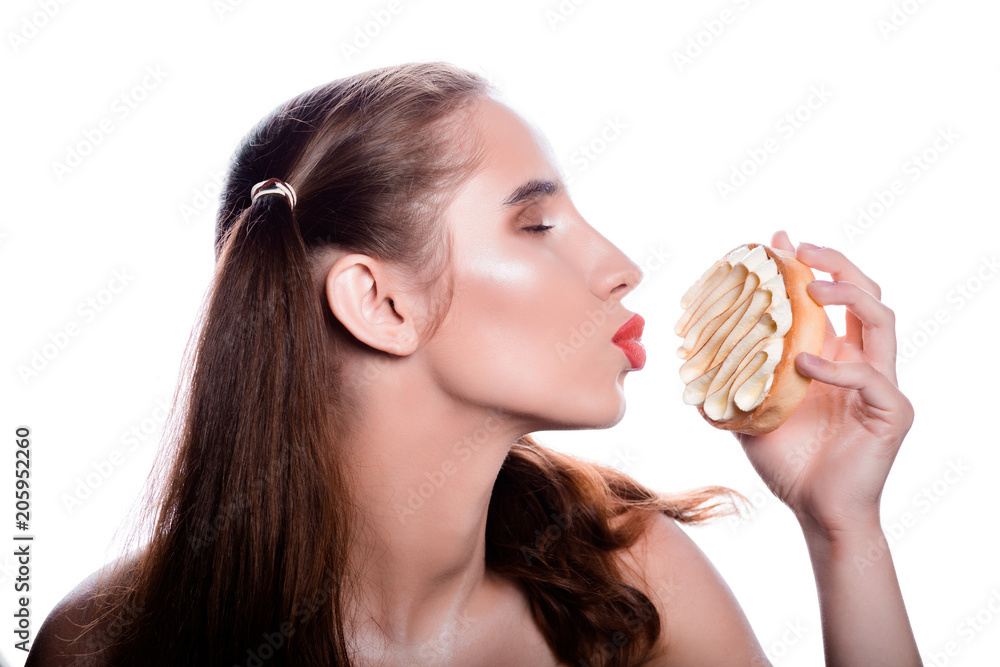 Adorable brunette girl with red lips kissing a tart cake with sour cream