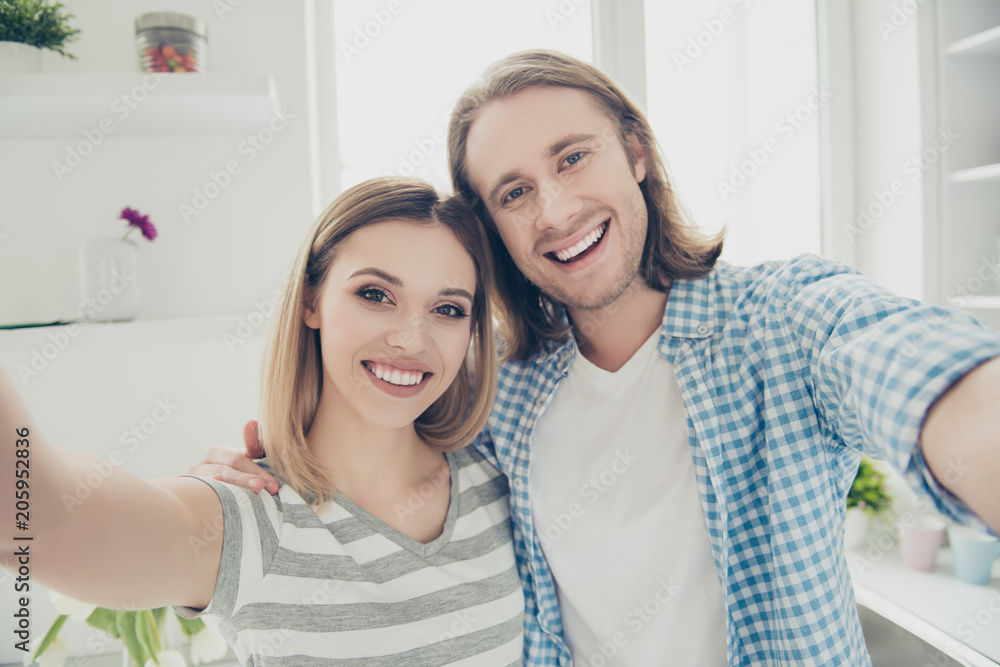 Self portrait of funky trendy couple with beaming smiles hugging shooting selfie on front camera with hands enjoying free time together Self portrait of funky trendy couple with beaming smiles hugging shooting selfie on front camera with hands enjoying free time together