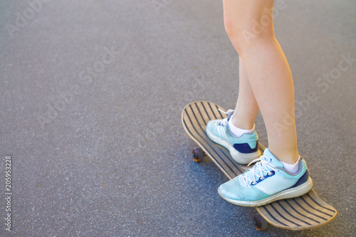 skateboarding, the feet of a girl standing on a skate board in sport sneakers.