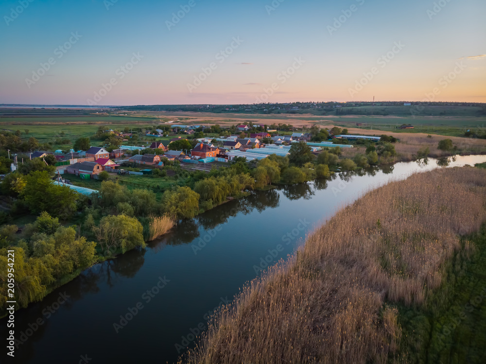 Small cozy village on the river side. Beautiful landscape with a bird's eye view on a summer evening