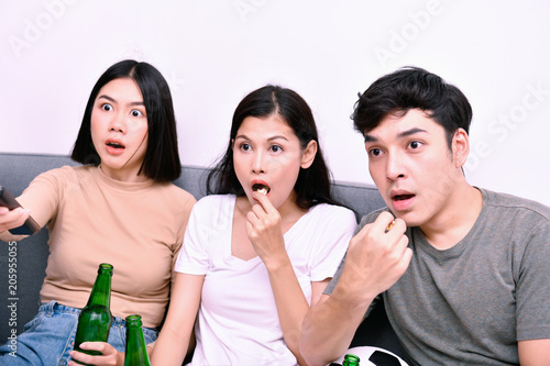 Concept of cheering. Asian teenagers watching football on television. People are cheering and winning football scores.