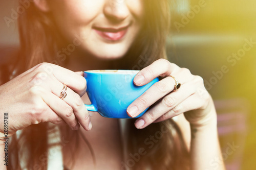 Portrait of smiling girl with cup of coffee at home. Visual effects. Blurred background.Cropped