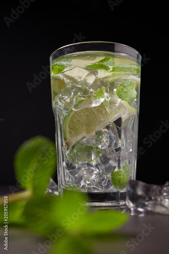 Cold and refreshing detox water with lime and mint in a glass on dark