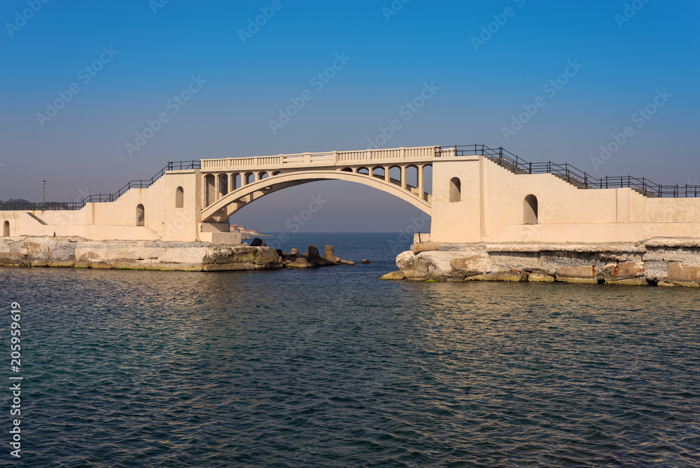 Bridge in the sea at Montazah park with calm sea and clear sky at sunrise time, Alexandria, Egypt