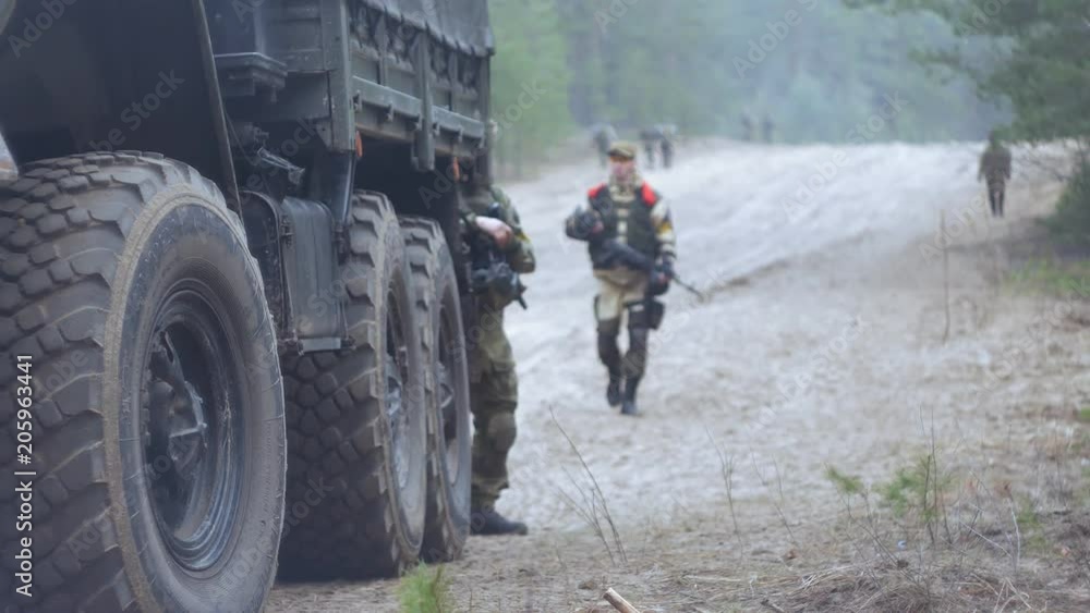 Soldiers in camouflage with combat weapons in the forest near the battle car, military concept Soldiers in camouflage with combat weapons in the forest near the battle car, military concept