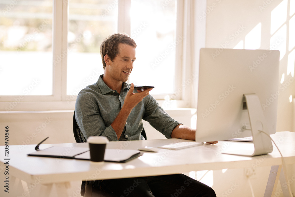Entrepreneur talking on mobile phone while working on computer a Entrepreneur talking on mobile phone while working on computer a