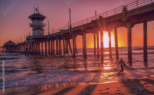 Silhouette of a surfer at sunset in front of the Huntington Beach Pier in California photo