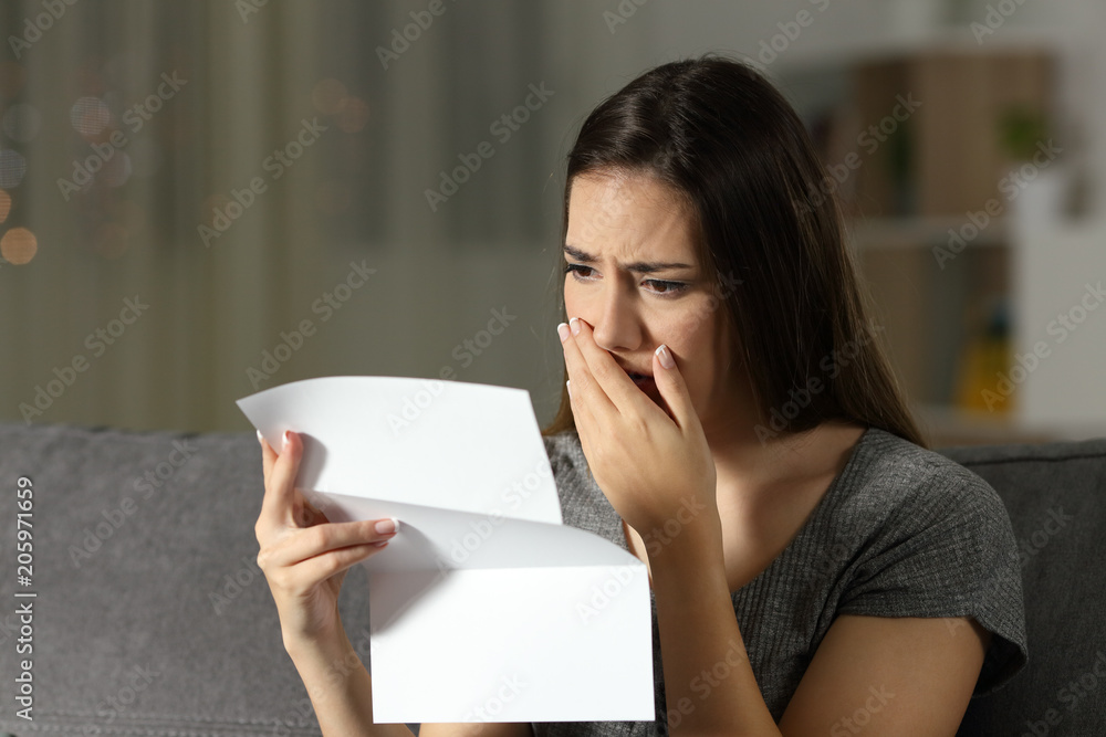 Sad woman complaining reading a letter in the night Sad woman complaining reading a letter in the night