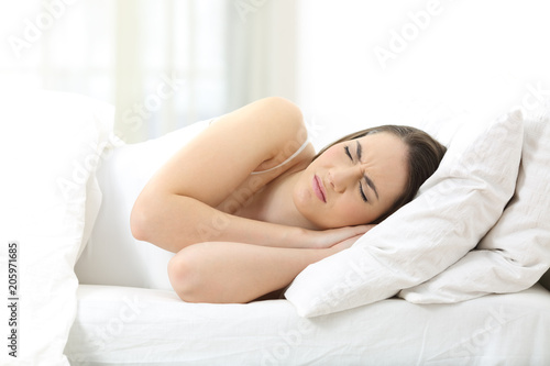 Unhappy woman sleeping on an uncomfortable mattress