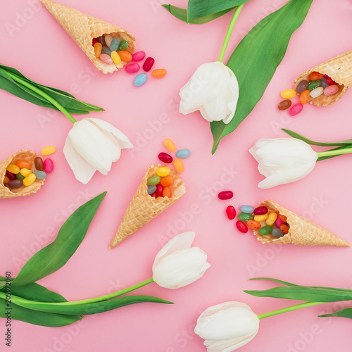 Fototapeta Naklejka Na Ścianę i Meble -  Composition with bright sugar candy in waffle cones and white flowers on pink background. Flat lay, top view