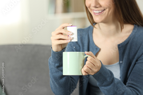 Woman throwing sacharine pill into a mug photo