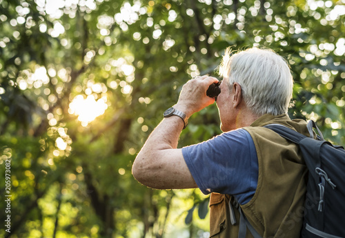 Elderly man watching birds with binoculars