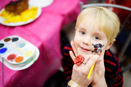 Face painting for cute little boy during kids birthday party photo