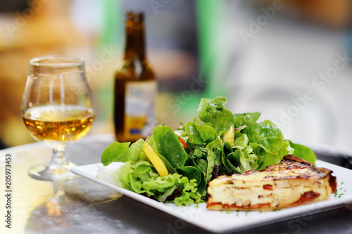 Traditional French food  quiche lorraine and fresh salad leaves with glass of beer on background