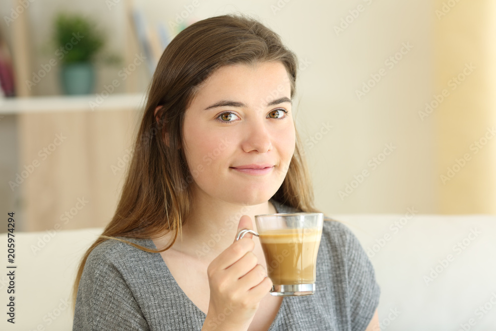 Happy teen holding a coffee with milk cup looking at you Happy teen holding a coffee with milk cup looking at you