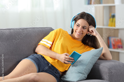 Happy teen in yellow listening to music at home