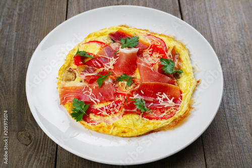 Healthy breakfast, restaurant menu photo, delicious nourishing meals with proteins and low fat. Appetizing omelet with prosciutto and tomatoes, close up