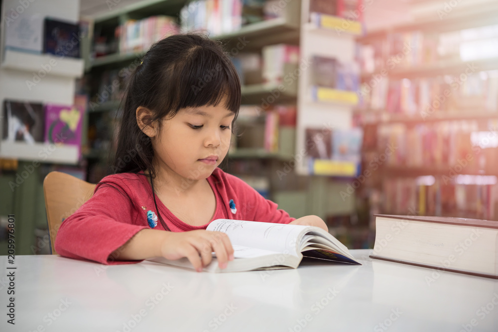 Cute little girl studying at the library and smiling Cute little girl studying at the library and smiling
