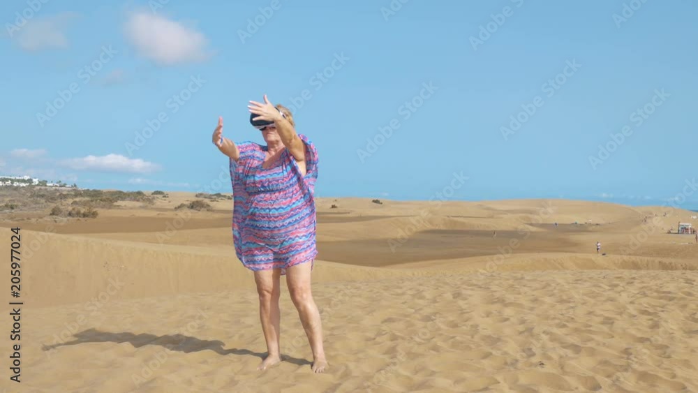 Professional video of senior woman wearing virtual googles on desert in 4k slow motion 60fps Professional video of senior woman wearing virtual googles on desert in 4k slow motion 60fps