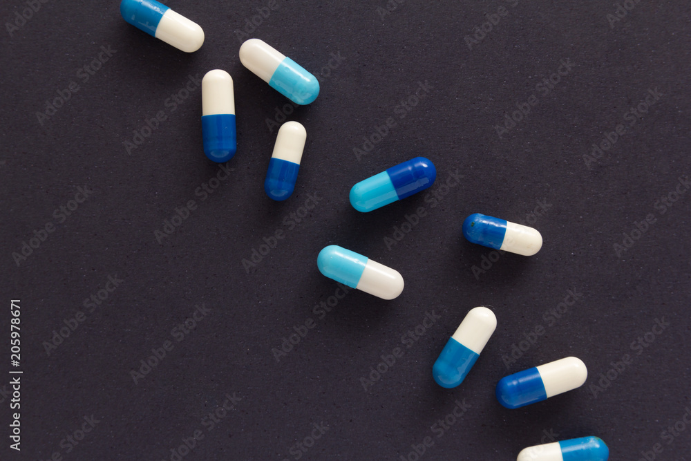 Heap of pills spreaded over color table. Group of assorted white and blue tablets. Heap of pills spreaded over color table. Group of assorted white and blue tablets.