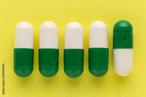 Heap of white and green capsules on white background. Pills are making a line or path. Concept of way, course.