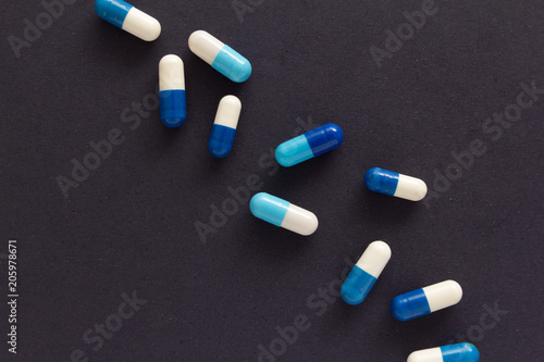 Heap of pills spreaded over color table. Group of assorted white and blue tablets.