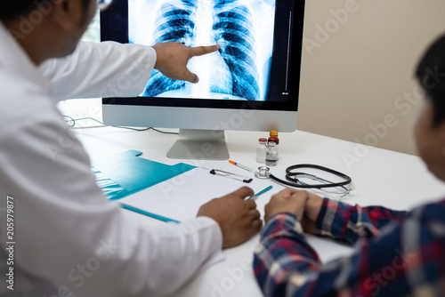 Professional doctor and radiologist giving a consultation to his patient, He pointed to the results of x-ray at the computer screen.. photo
