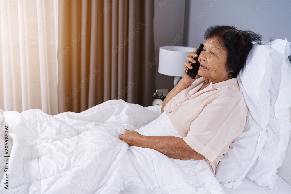 senior woman talking on mobile phone in bed senior woman talking on mobile phone in bed