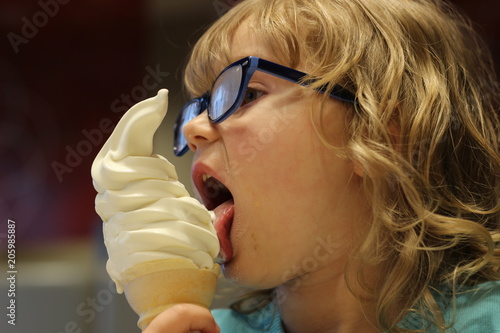 Young girl aged 3 to 6 years old eats ice cream on a summer day at a parlour