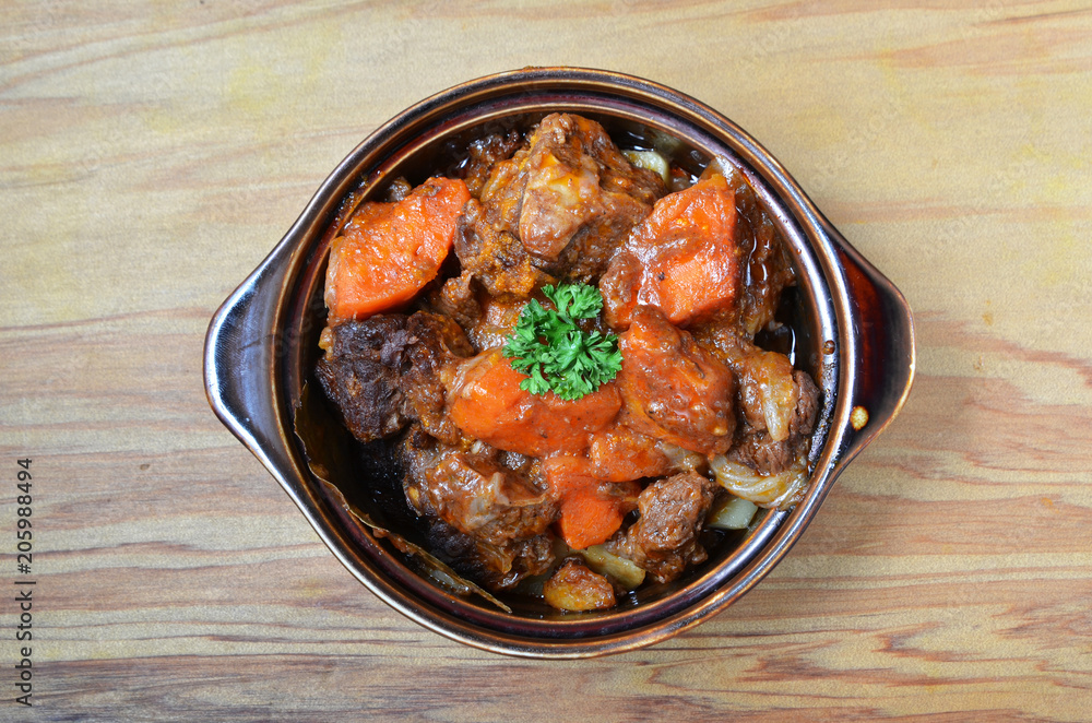 A bowl of beef stew on a wooden table 