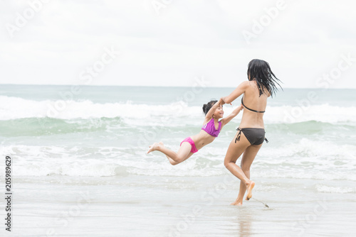 Mother and daughter walking on the beach.