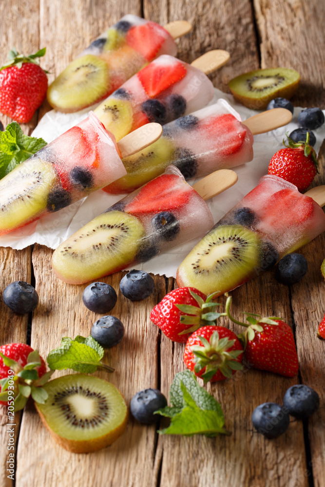 Healthy Whole Fruit Popsicles with Berries Kiwi strawberries closeup on wooden table. vertical Healthy Whole Fruit Popsicles with Berries Kiwi strawberries closeup on wooden table. vertical