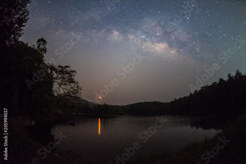 Milky Way band across sky and Moonrise over reservoir.