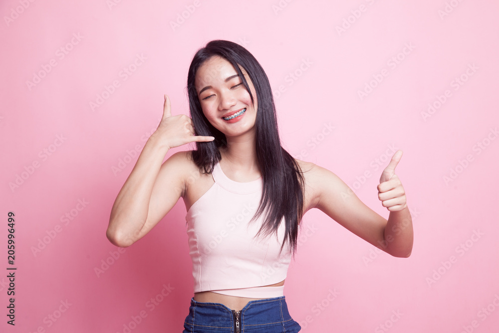Young Asian woman thumbs up show with phone gesture. Young Asian woman thumbs up show with phone gesture.