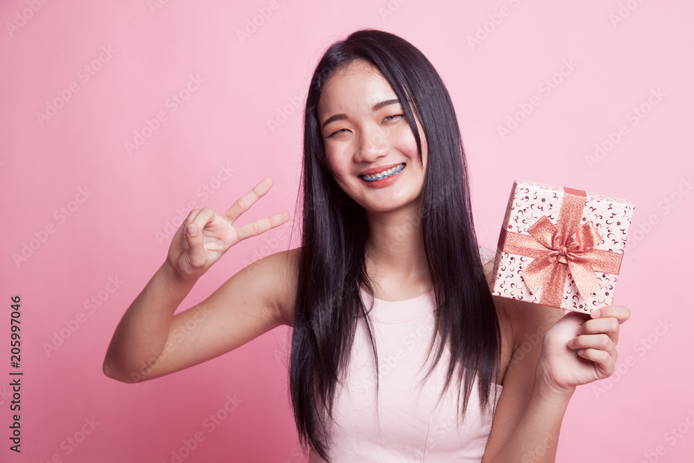 Asian woman show victory sign with a gift box. Asian woman show victory sign with a gift box.